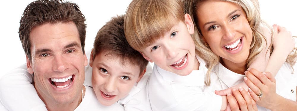 A healthy family smiling together, showing off their bright, well-cared-for teeth.