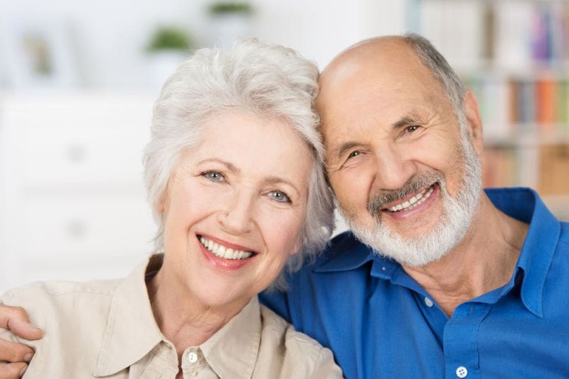 Smiling senior man and woman sitting on couch together