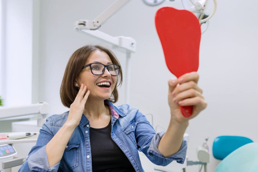 Melrose dental office | Woman smiling at mirror.