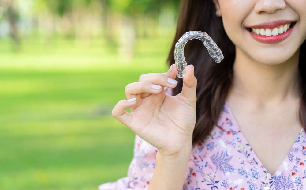 Invisalign For Adults | Woman holding clear aligners.