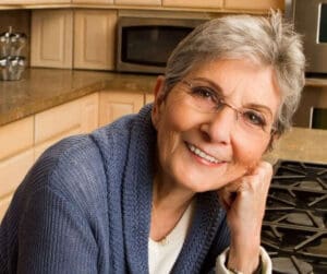 dentures in Melrose - Woman smiling in kitchen