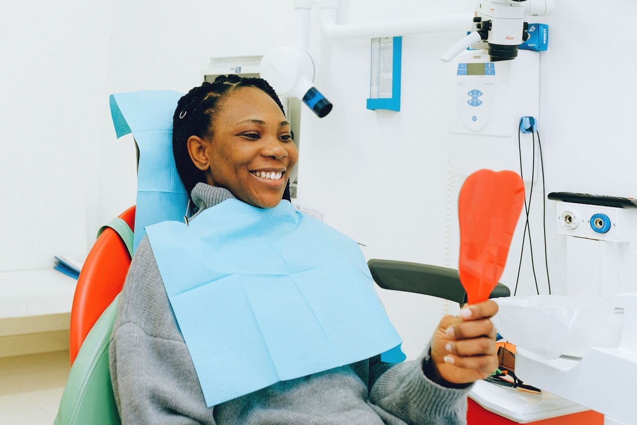 Woman in dental chair looking at her smile in a mirror