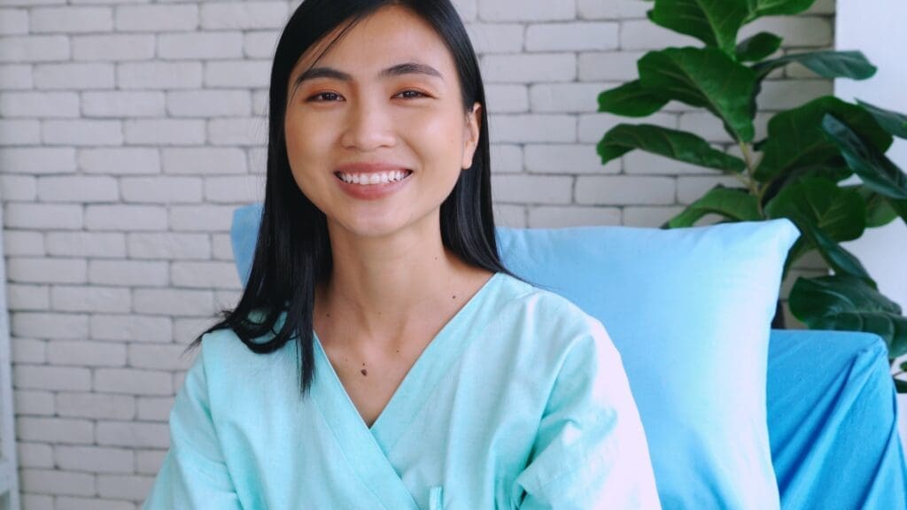 Young woman in mint green scrubs smiling and sitting in dental office