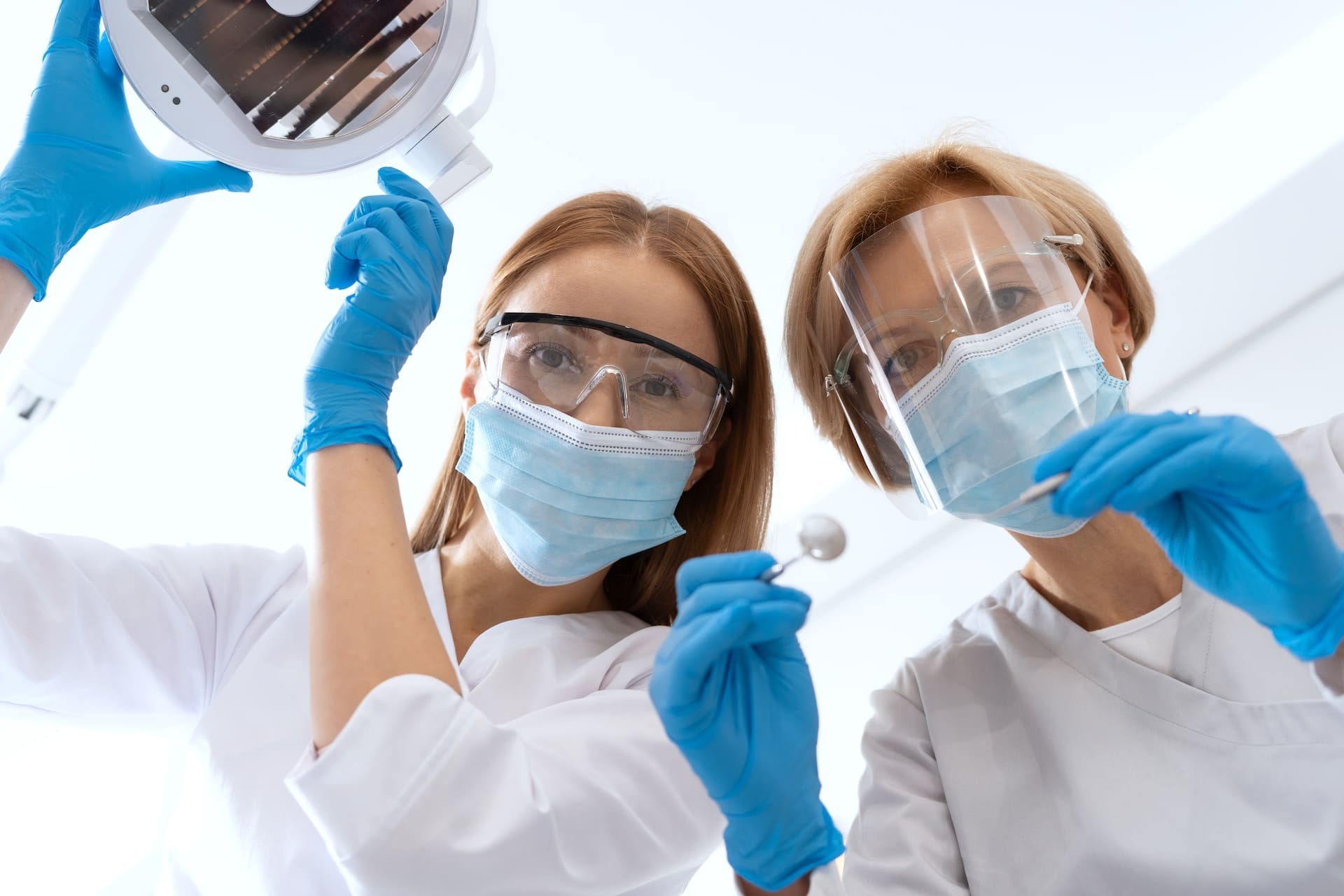 Two dentists consulting over a patient in the dental chair