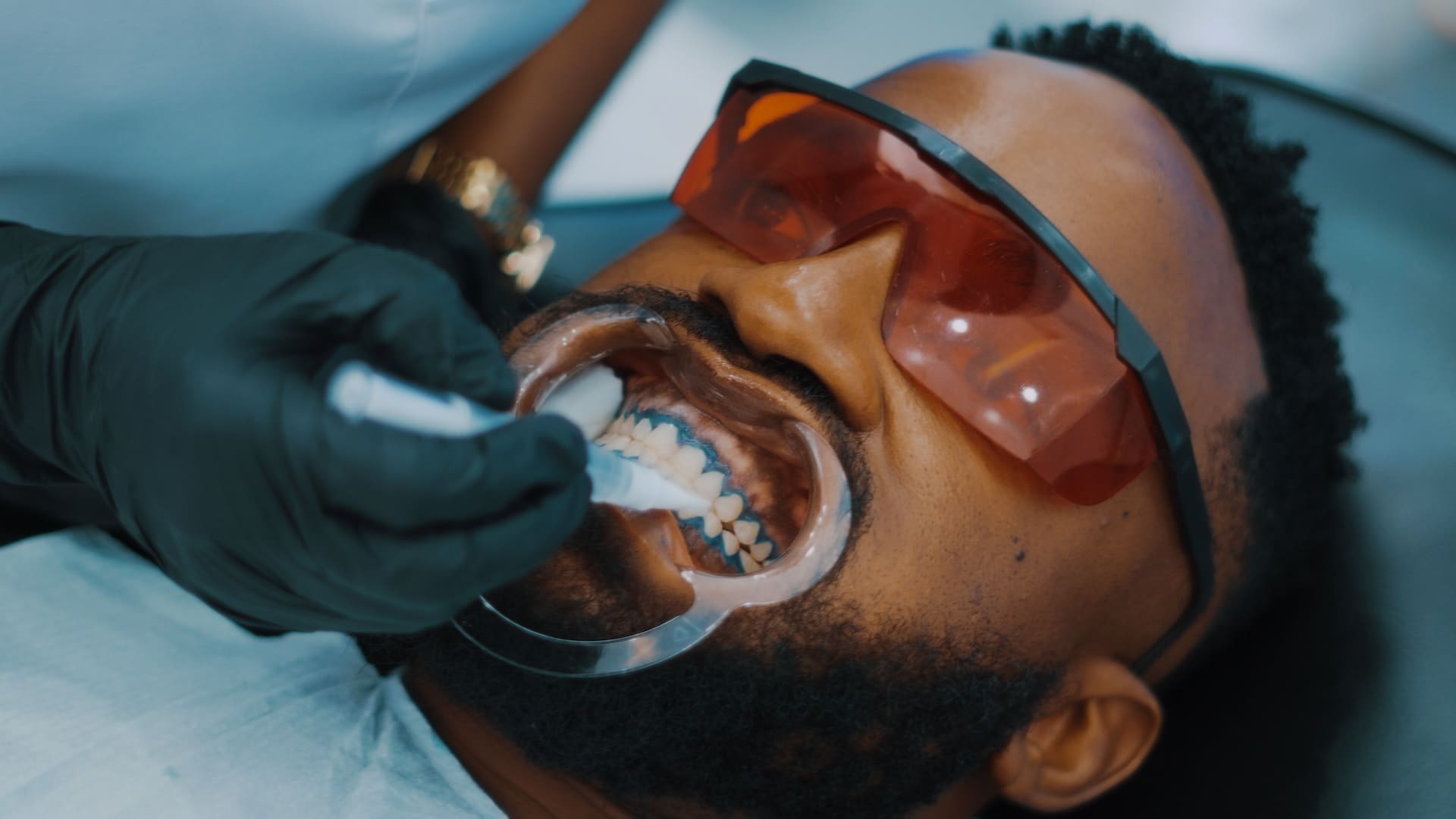 A person receiving gum treatment from a dentist, focusing on their gums with dental tools.