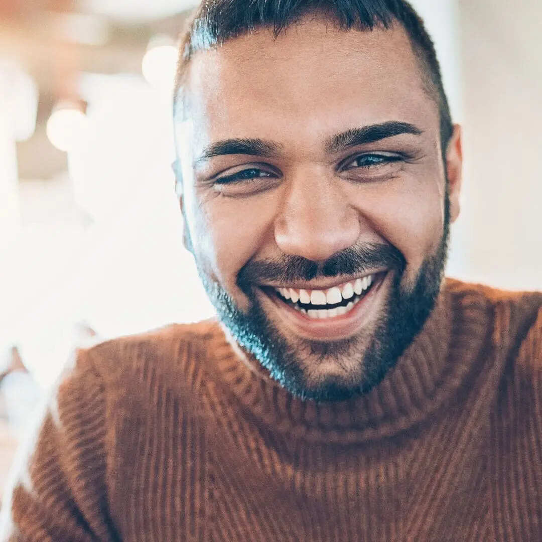 Man smiling in dental chair, dental assistant nearby.