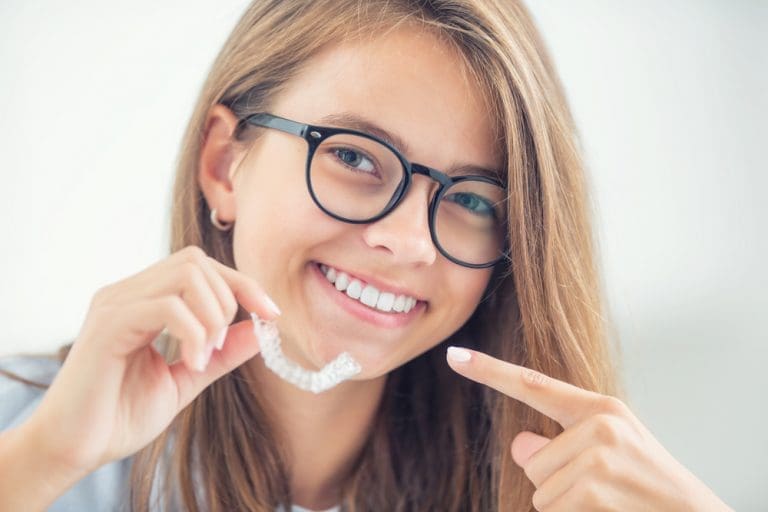 Smiling woman holding Invisalign braces.