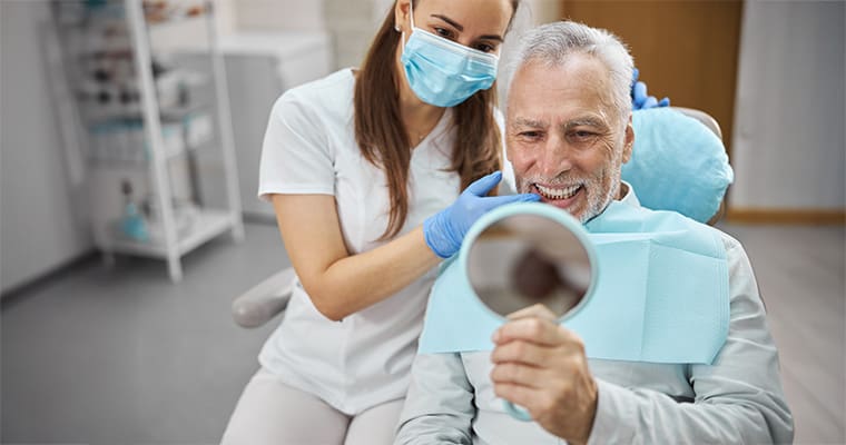A dentist showing a patient his teeth in a mirror.