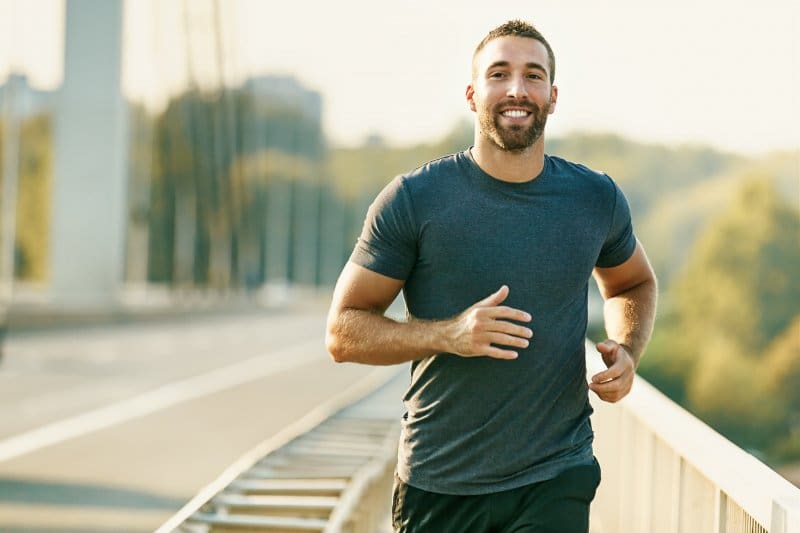 A young and smiling man exercising outdoors