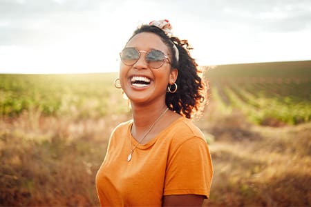 Woman in orange shirt smiling in field