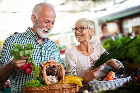 Couple at outdoor market shopping for food.