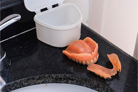 Dentures sitting next to a protective case.