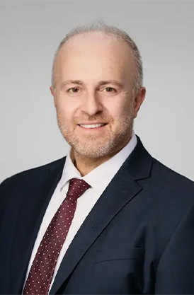 Profile image of Dr. Konstantinos Vazouras smiling in a suit and tie.