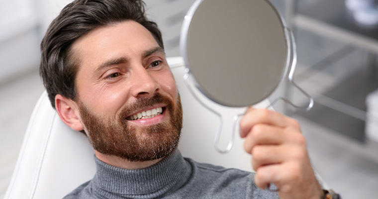 Middle-aged man pleased with new smile after receiving dental crowns in Melrose.