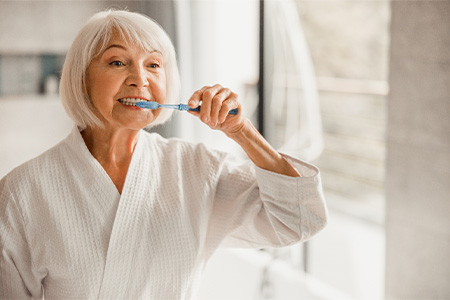Older woman brushing her teeth.