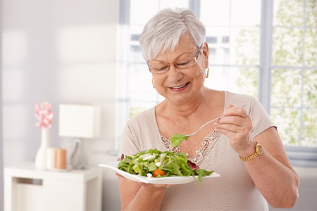 Older woman eating a healthy salad.