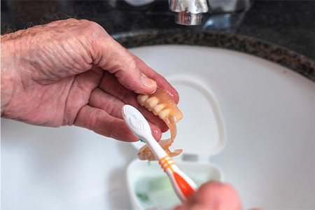 Person cleaning their dentures.