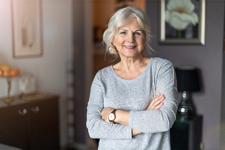Senior woman smiling with arms folded.